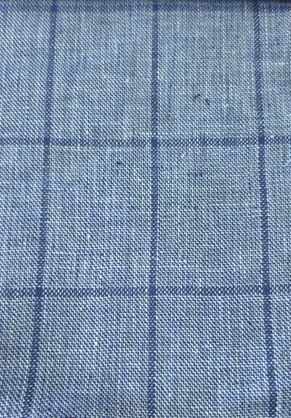 A close-up of a blue woven fabric with a subtle windowpane plaid pattern.