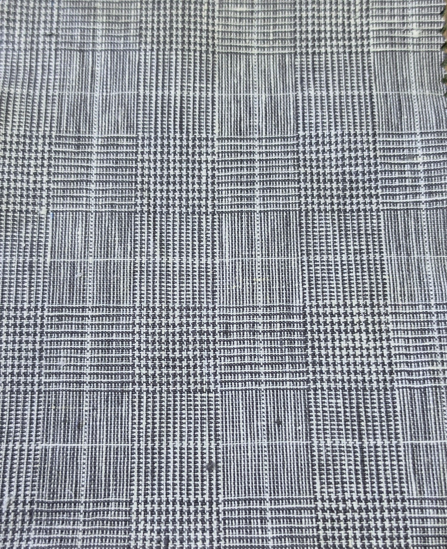 A close-up of a woven fabric with a black and white plaid pattern, showing the texture and weave detail.