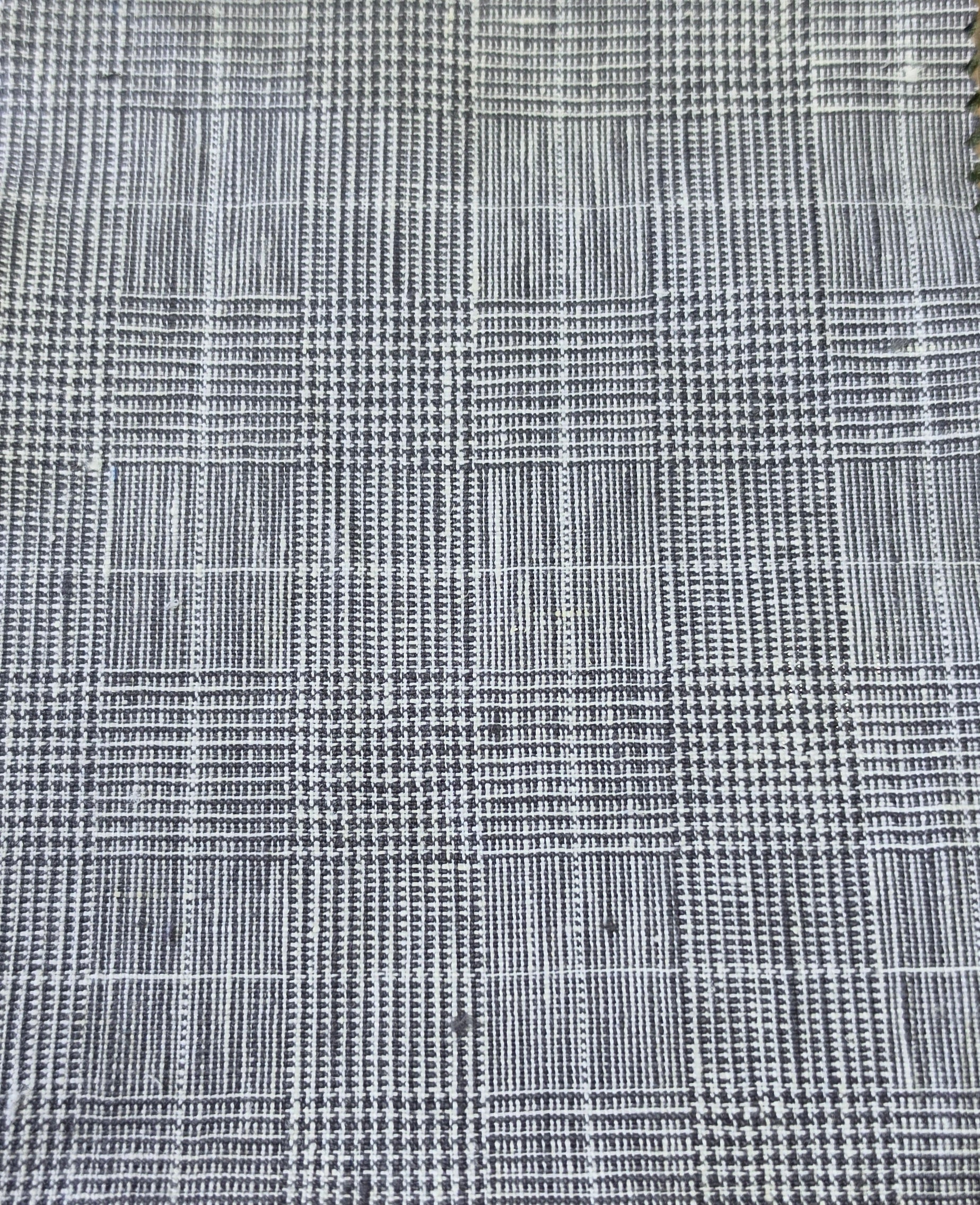A close-up of a woven fabric with a black and white plaid pattern, showing the texture and weave detail.