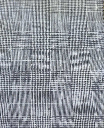 A close-up of a woven fabric with a black and white plaid pattern, showing the texture and weave detail.