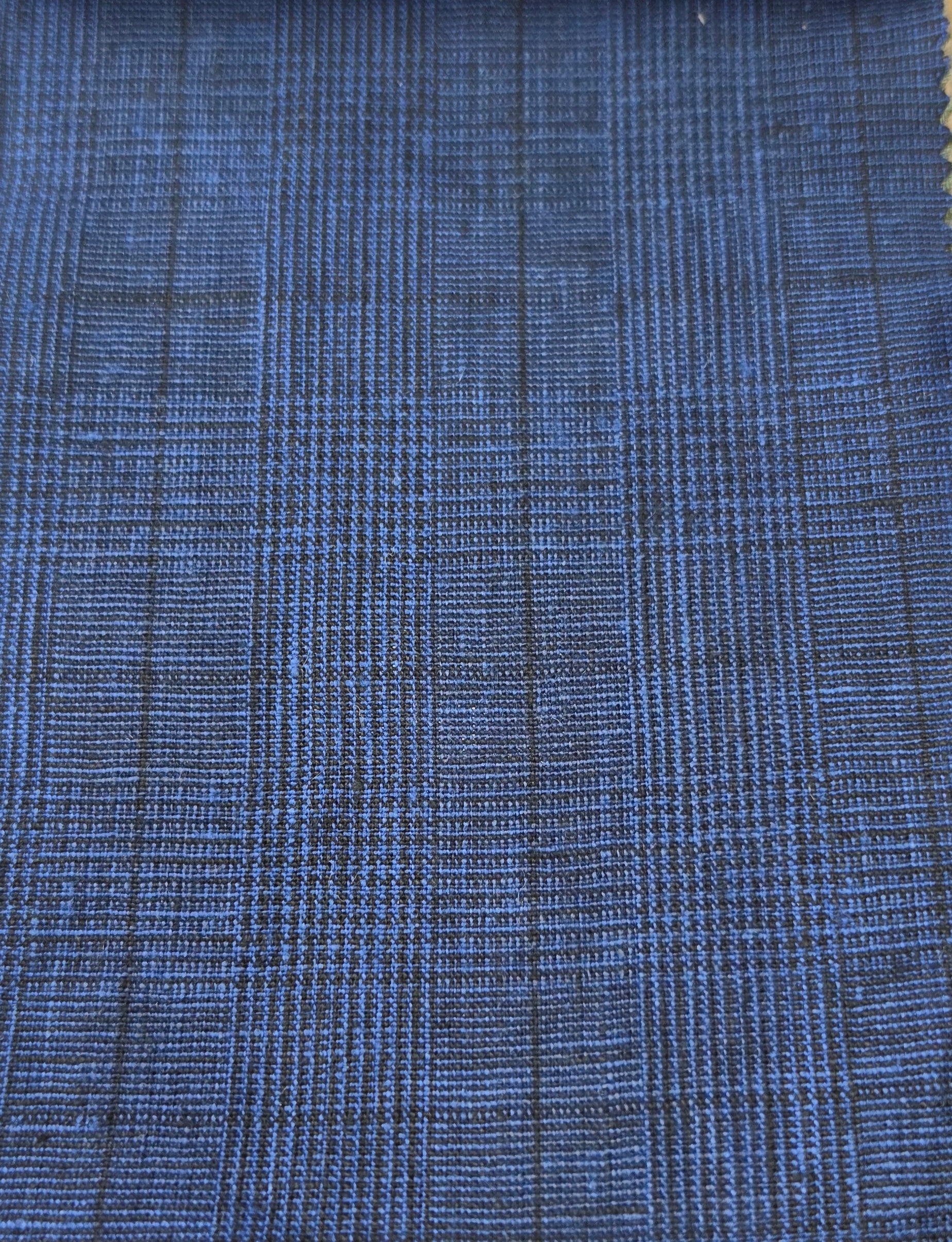 A close-up of a blue woven fabric with a subtle black plaid or grid pattern.