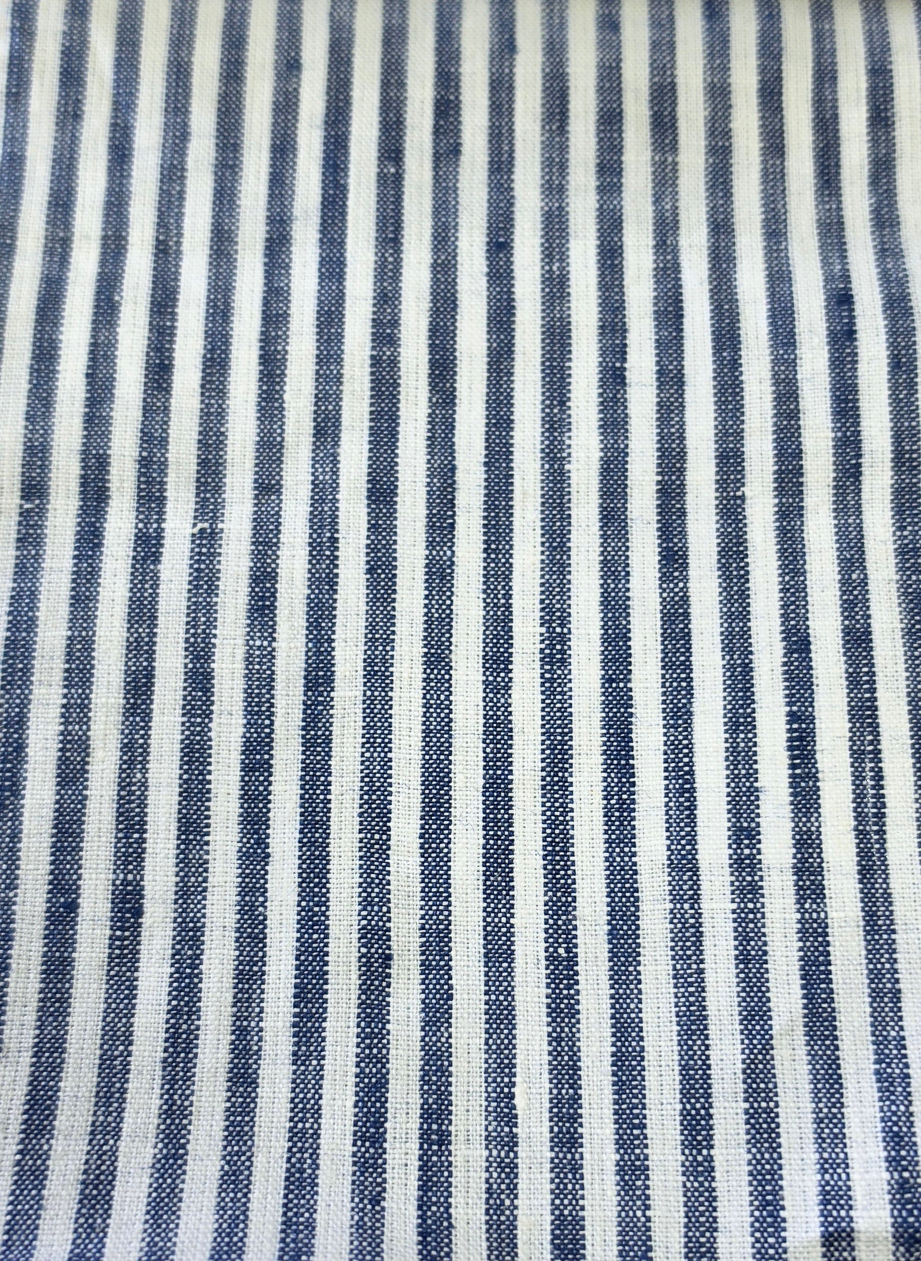 A close-up of a woven fabric with vertical navy blue and off-white stripes, showing the textile texture.