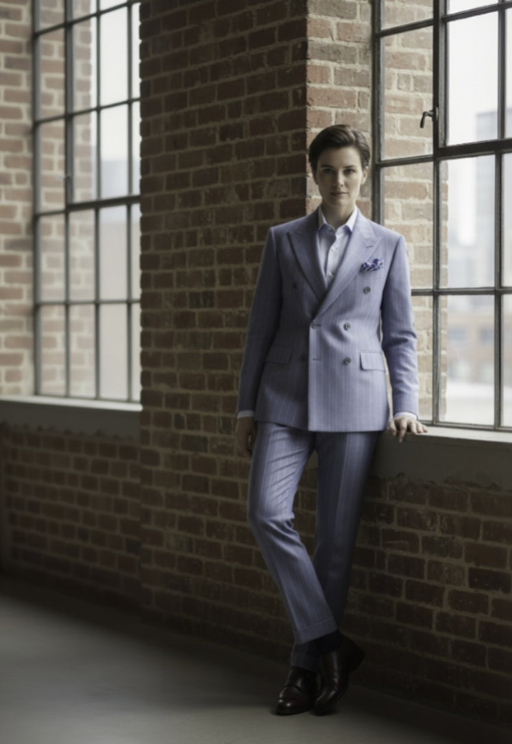 Ladies light blue suit standing against a brick wall with large windows.