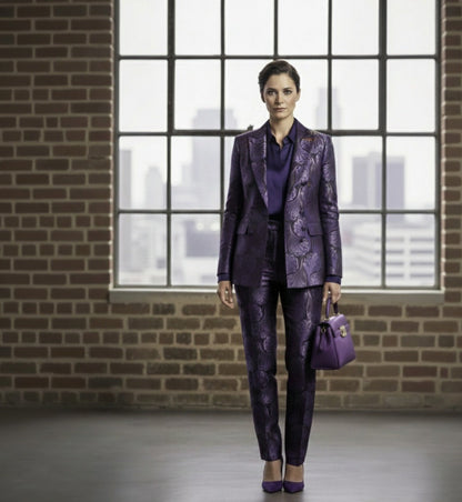 Lady in a purple suit standing in front of a large window with a cityscape view.