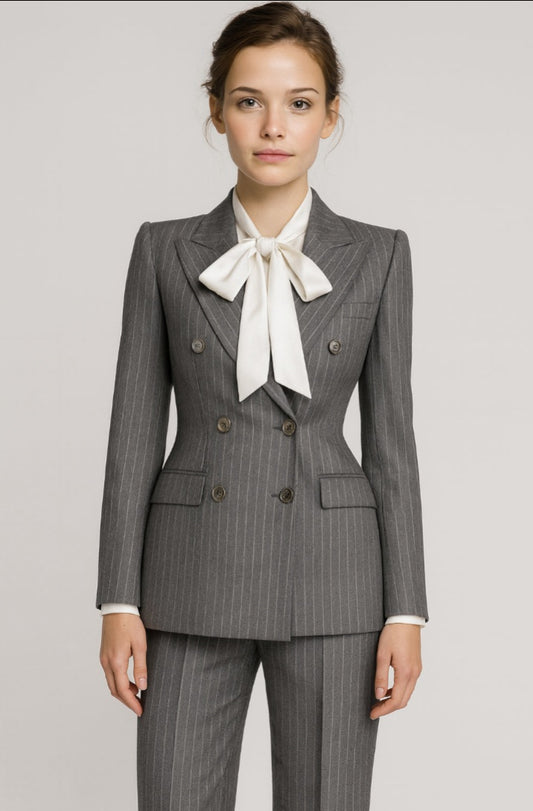 Lady wearing a grey pinstripe suit with a white bow tie on a plain background
