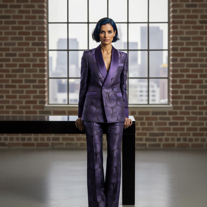 Lady wearing a purple patterned suit standing in front of a large window with cityscape view.