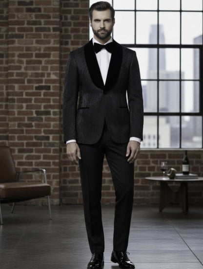 Man in a black tuxedo standing in a room with brick walls and large windows.