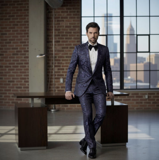 Man in a dark blue patterned suit standing in an urban setting with large windows.