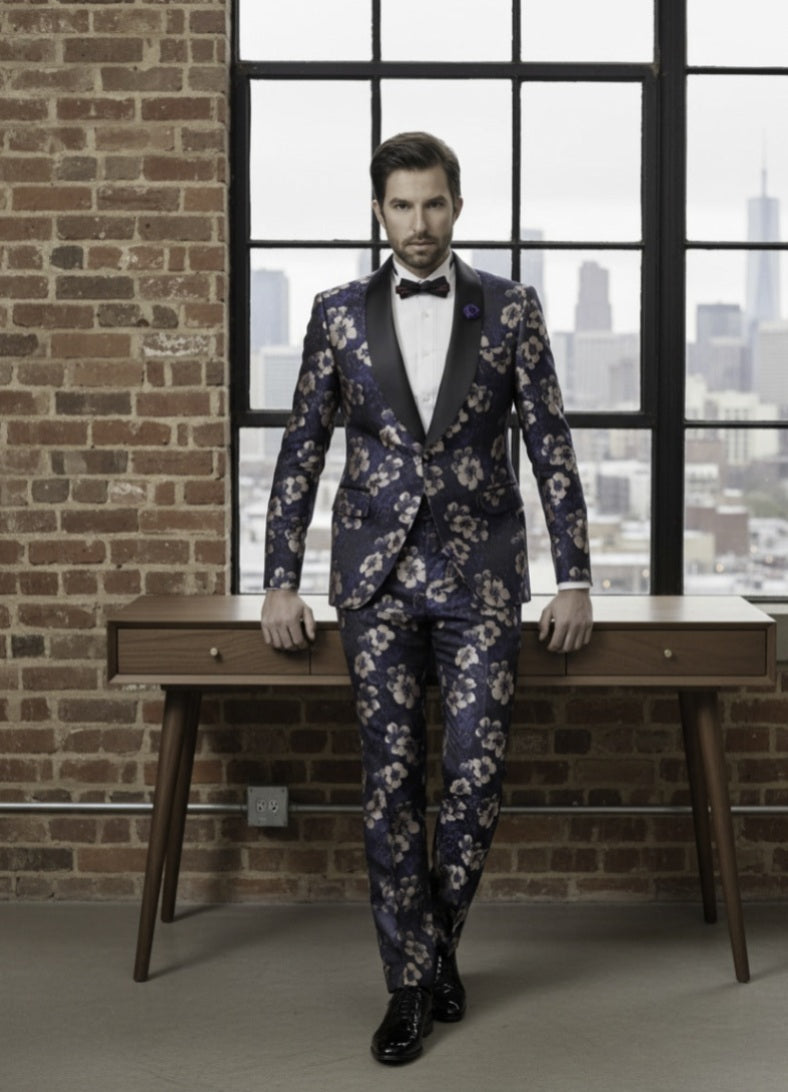 Man in a floral suit standing in front of a window with a cityscape view.