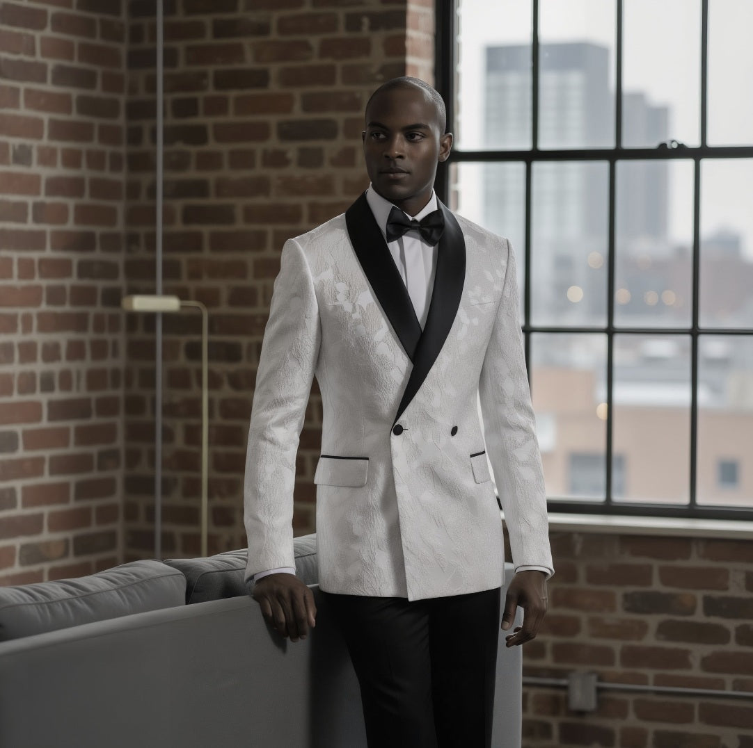Man in a white suit standing in a room with large windows and brick wall