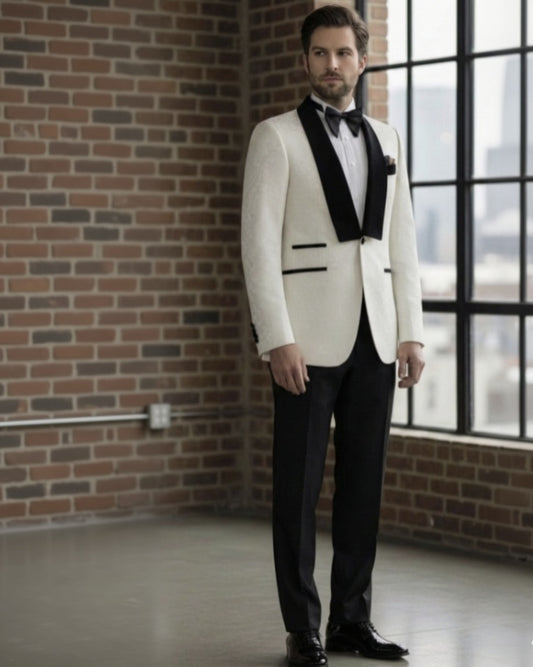 Man in a white tuxedo with black lapels standing in a room with brick walls and large windows