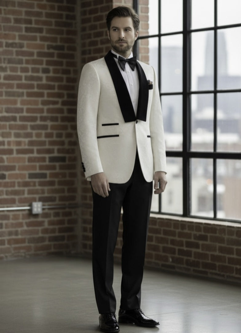 Man in a white tuxedo with black lapels standing in a room with brick walls and large windows