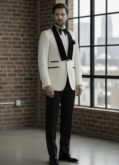 Man in a white tuxedo with black lapels standing in a room with brick walls and large windows