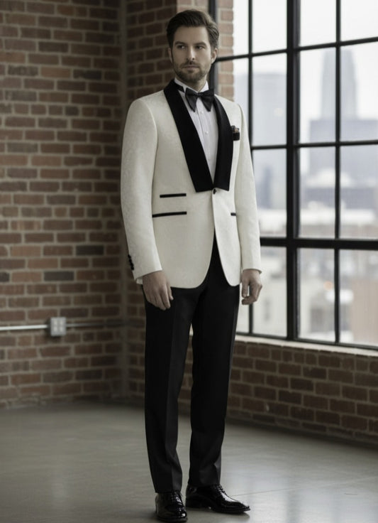 Man in a white tuxedo with black lapels standing in a room with brick walls and large windows