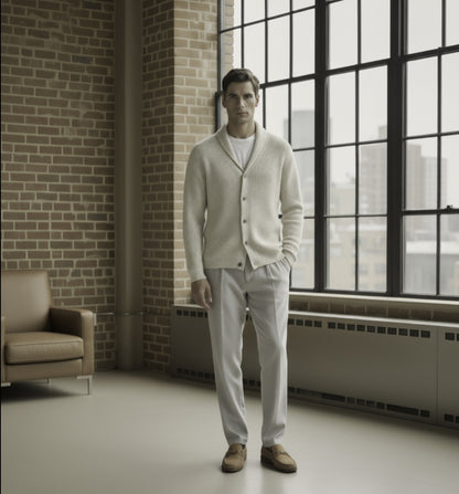 Man standing in a room with large windows and a brick wall.