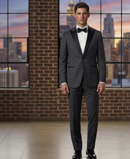 Man wearing a Grey tuxedo standing in front of a large window with a cityscape view.
