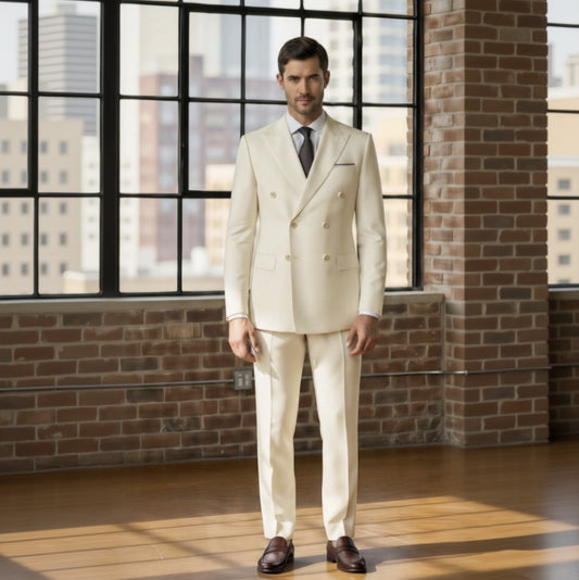 Man wearing a Ivory suit standing in front of a brick wall with large windows.