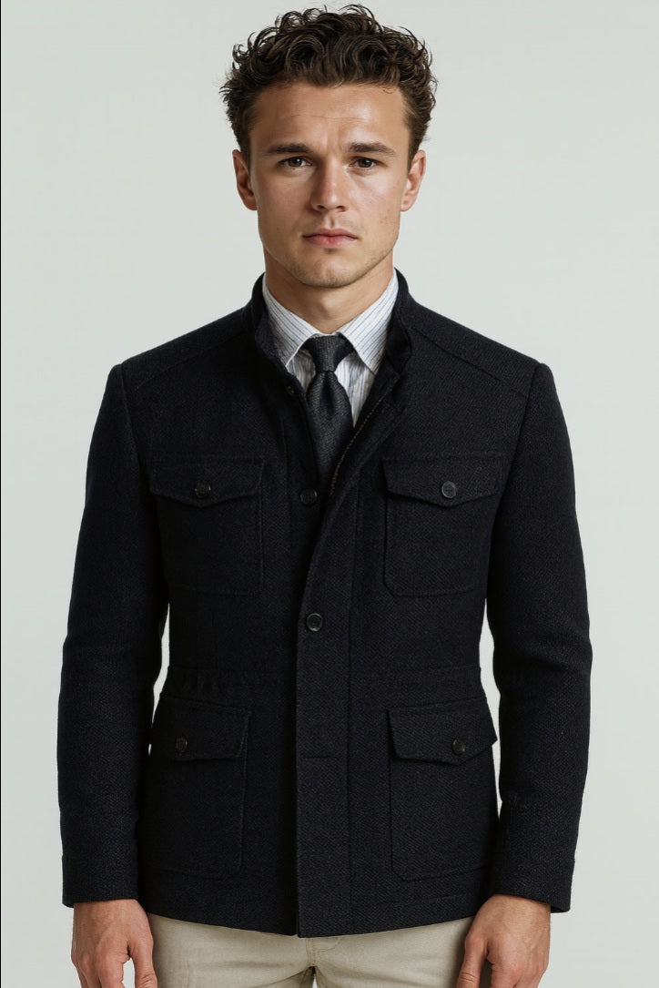 Man wearing a black jacket over a white shirt with a tie on a light gray background