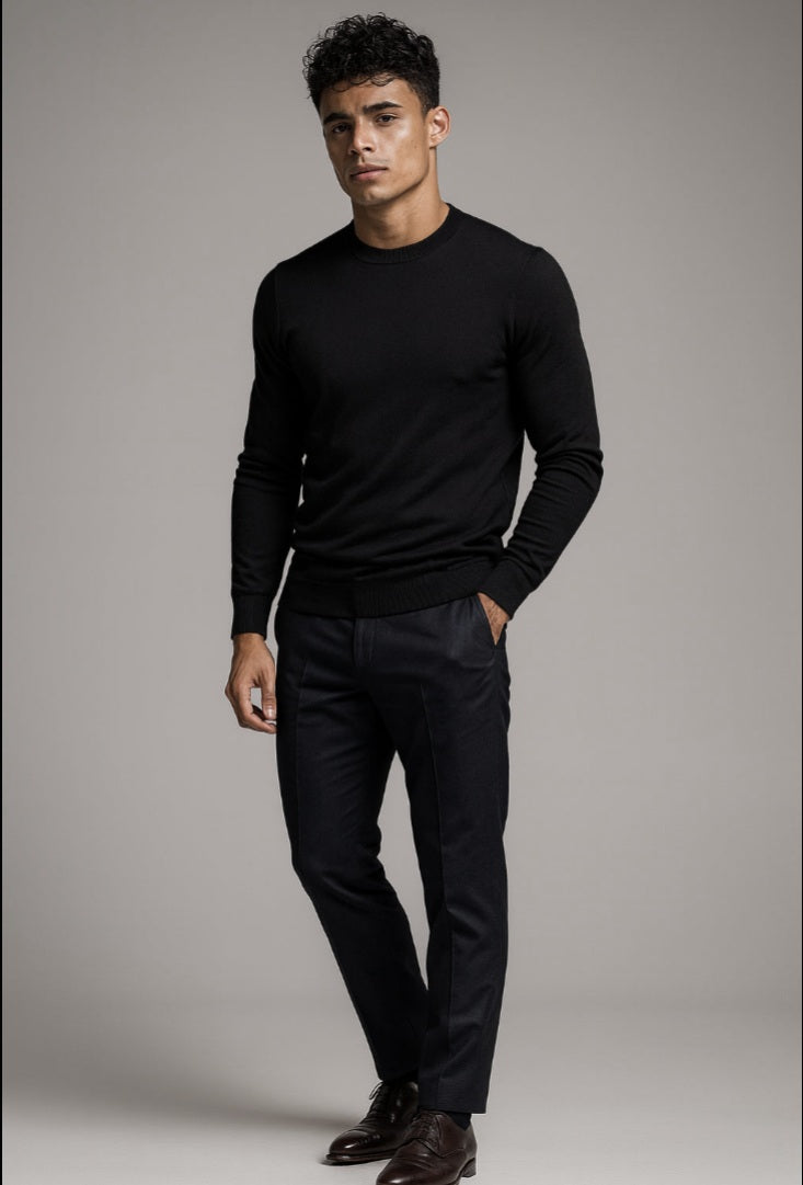 Man wearing a black sweater and pants against a gray background