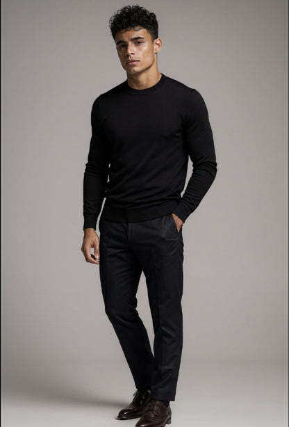 Man wearing a black sweater and pants against a gray background