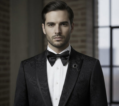 Man wearing a black tuxedo with a bow tie in an indoor setting.