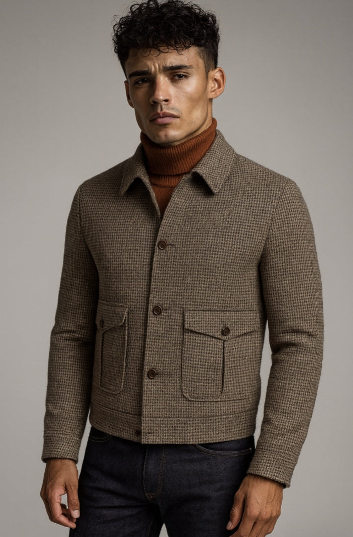 Man wearing a brown checkered jacket over a turtleneck against a gray background