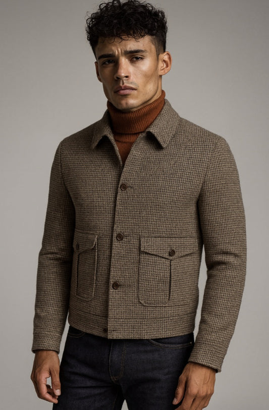 Man wearing a brown checkered jacket over a turtleneck against a gray background