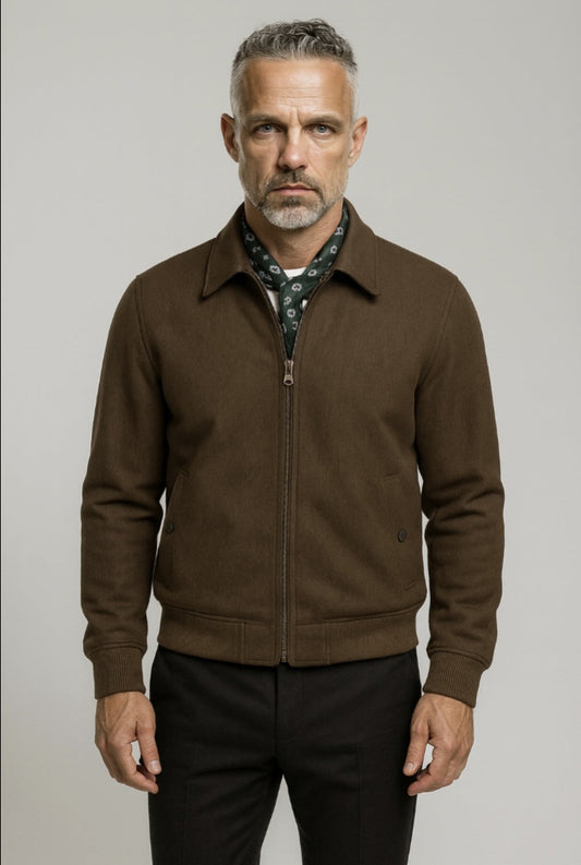 Man wearing a brown jacket over a patterned shirt on a gray background