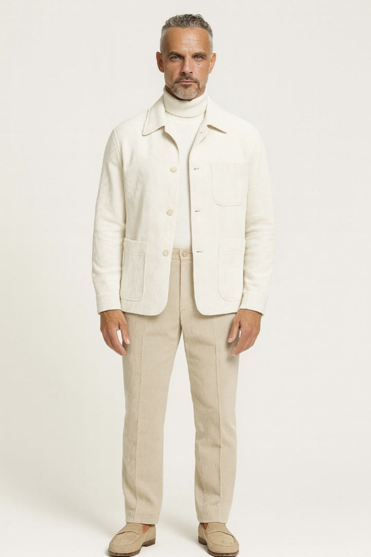 Man wearing a cream blazer, turtleneck, and beige pants on a white background