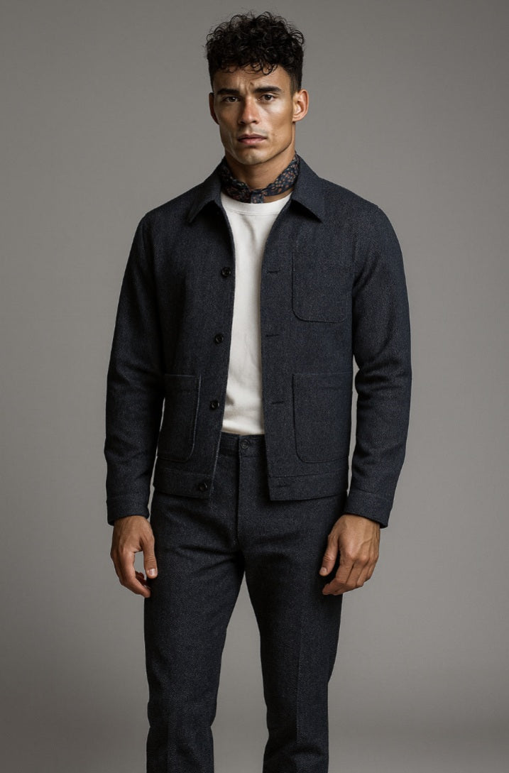 Man wearing a dark denim jacket over a white shirt on a gray background