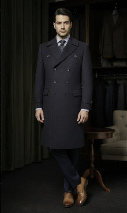 Man wearing a dark overcoat in a room with suit racks and a chair.