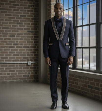 Man wearing a dark suit with a patterned tie in a room with brick walls and large windows.