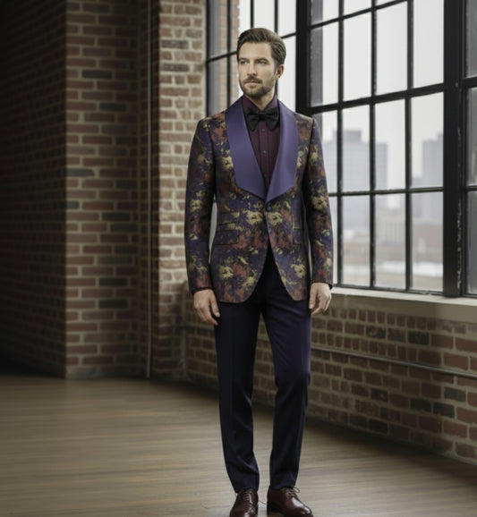 Man wearing a floral blazer with a purple lapel and bow tie in a room with brick walls and large windows.