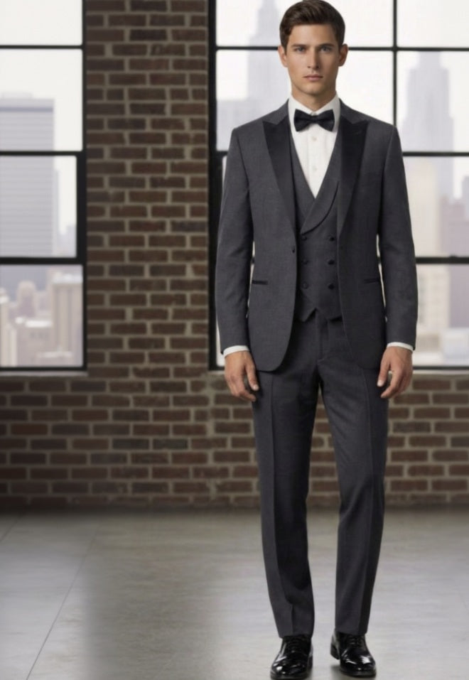 Man wearing a formal Charcoal suit with a bow tie in front of a brick wall.