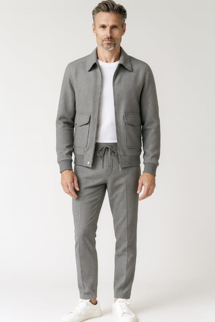 Man wearing a gray jacket and pants with a white shirt on a light gray background