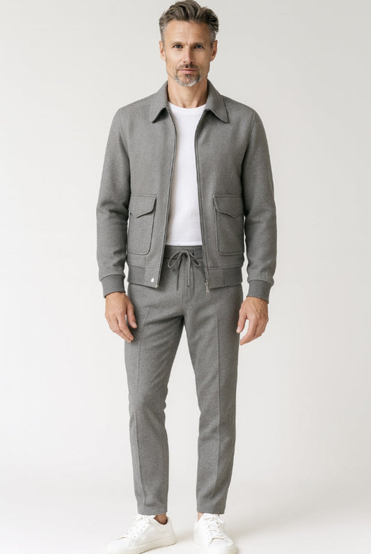 Man wearing a gray jacket and pants with a white shirt on a light gray background