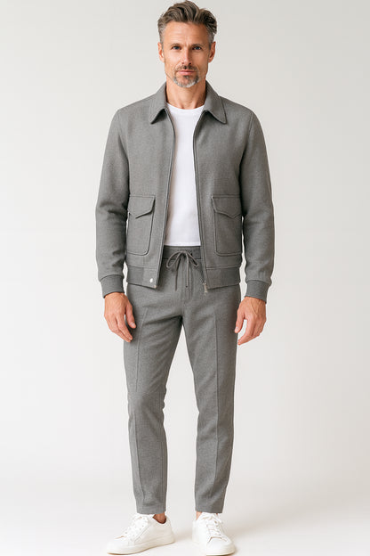 Man wearing a gray jacket and pants with a white shirt on a light gray background