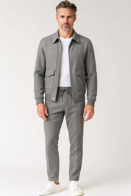 Man wearing a gray jacket and pants with a white shirt on a light gray background