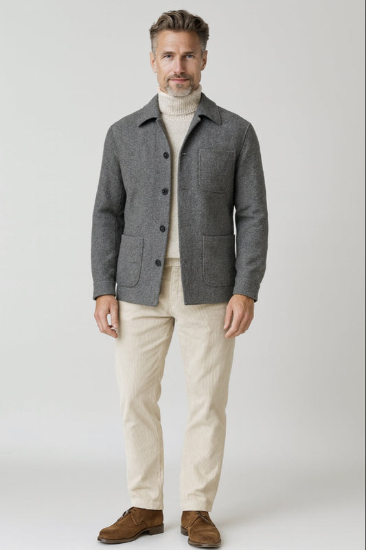 Man wearing a gray jacket, beige sweater, and pants on a white background