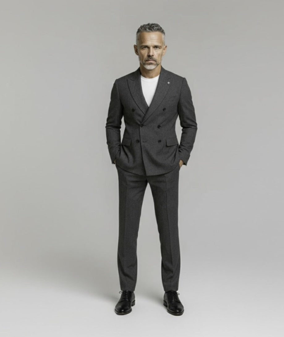 Man wearing a grey suit with a white t-shirt on a plain background