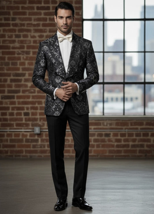 Man wearing a patterned suit with a white shirt and bow tie in front of a brick wall and window.