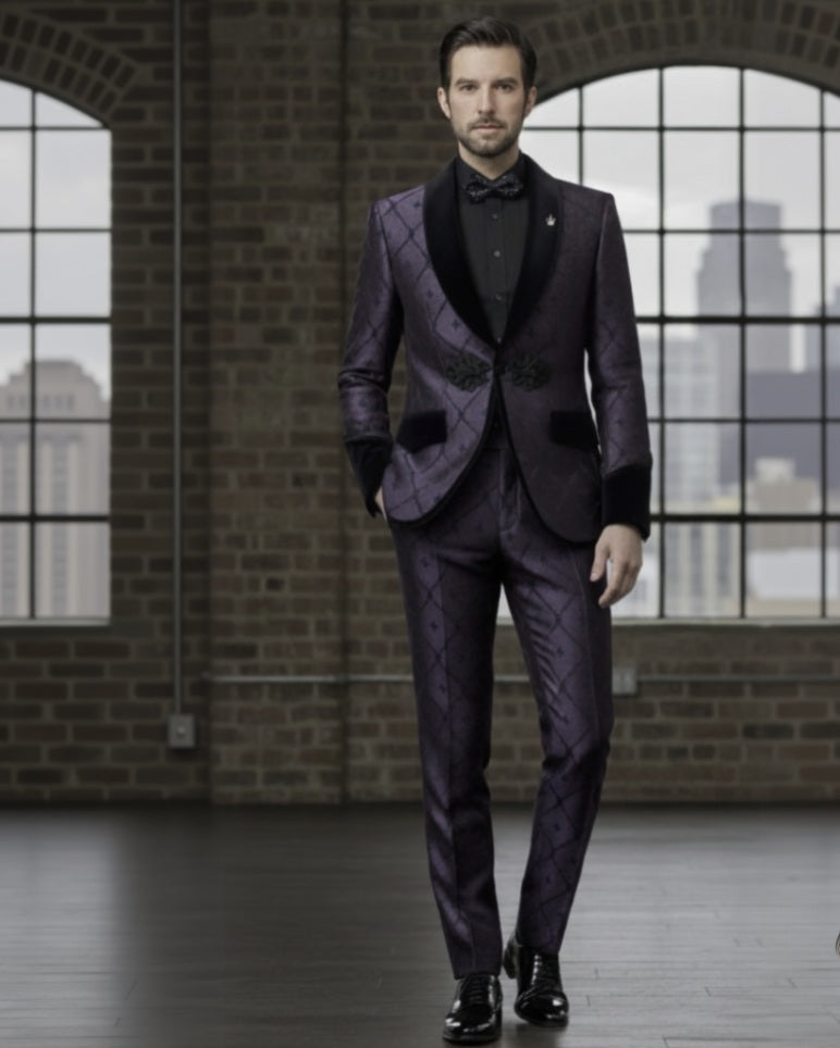 Man wearing a purple suit with a bow tie in an indoor setting with brick walls and large windows.