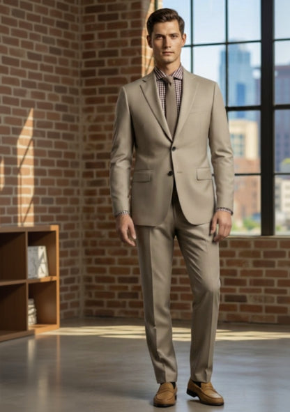 Man wearing a tan suit standing in a room with brick walls and large windows.