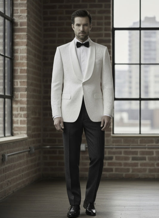 Man wearing a white tuxedo with a black bow tie in an urban setting.