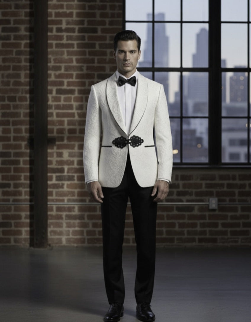 Man wearing a white tuxedo with black lapels and bow tie in front of a brick wall and window.