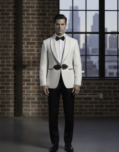 Man wearing a white tuxedo with black lapels and bow tie in front of a brick wall and window.