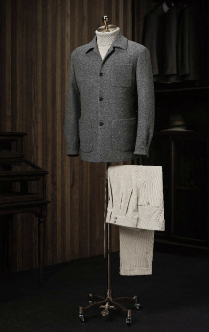 Mens Grey blazer and white pants on a mannequin in a dark room.