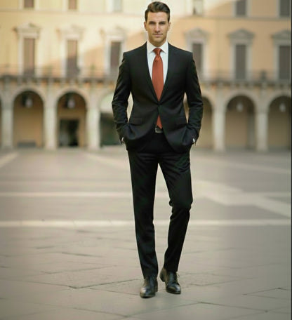 Man in a black suit with a red tie standing in an open square with arches.