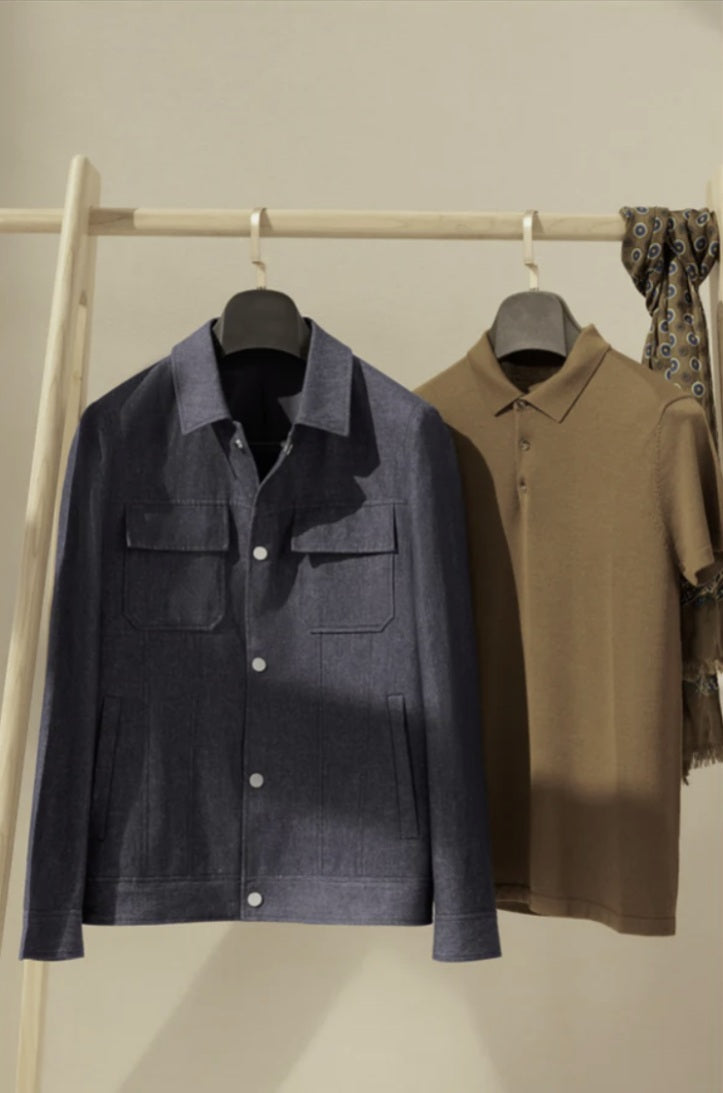 Navy jacket and brown shirt on hangers against a neutral background