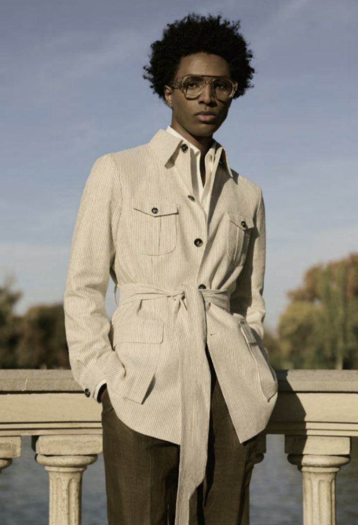 Person wearing a beige trench coat standing outdoors with a clear sky background